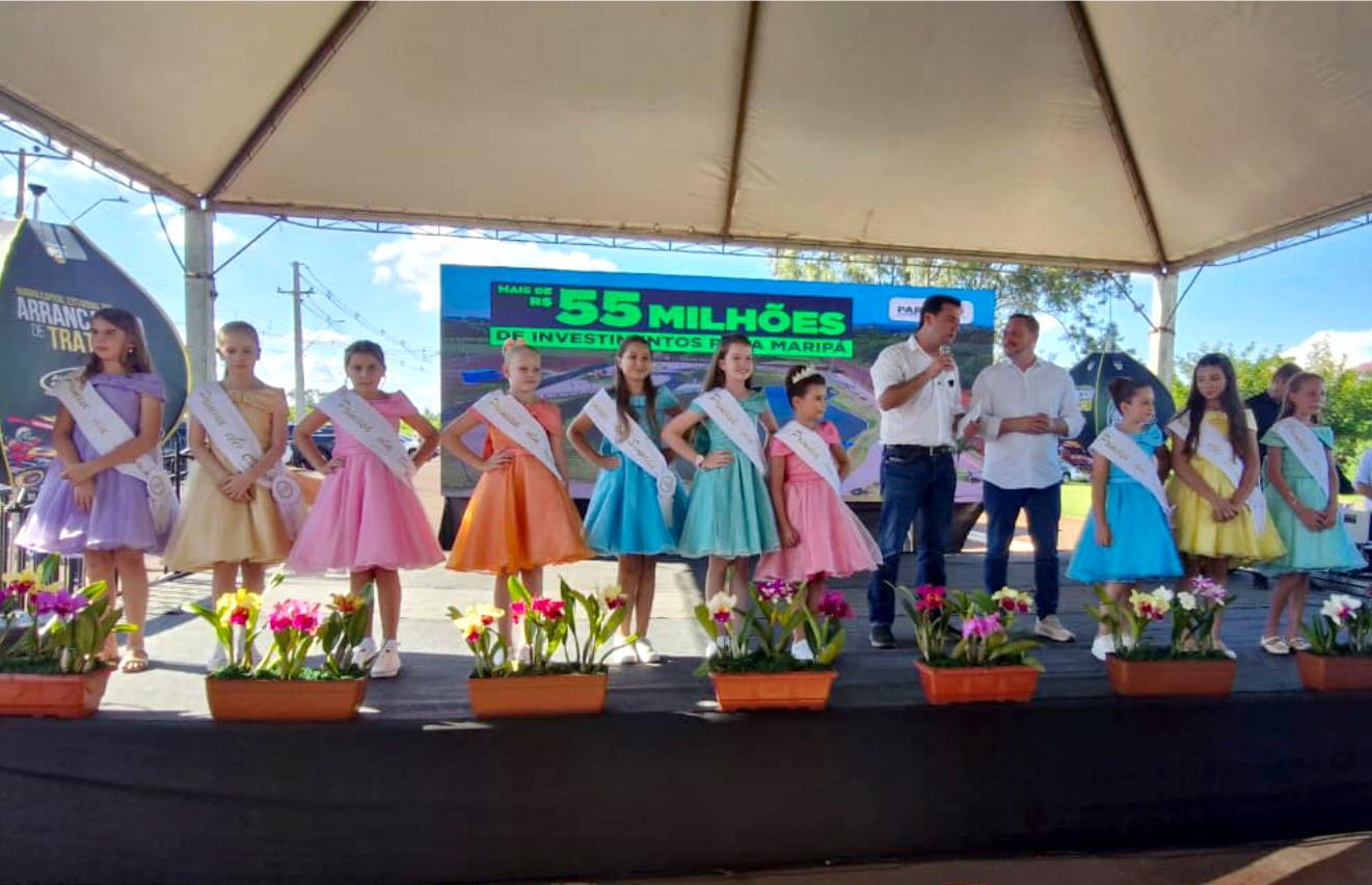 Governador Carlos Massa Ratinho Júnior participa de evento em Maripá ao lado do prefeito Rodrigo Schanoski e das princesas da Festa das Orquídeas e do Peixe, destacando a valorização das tradições locais e a parceria com o município