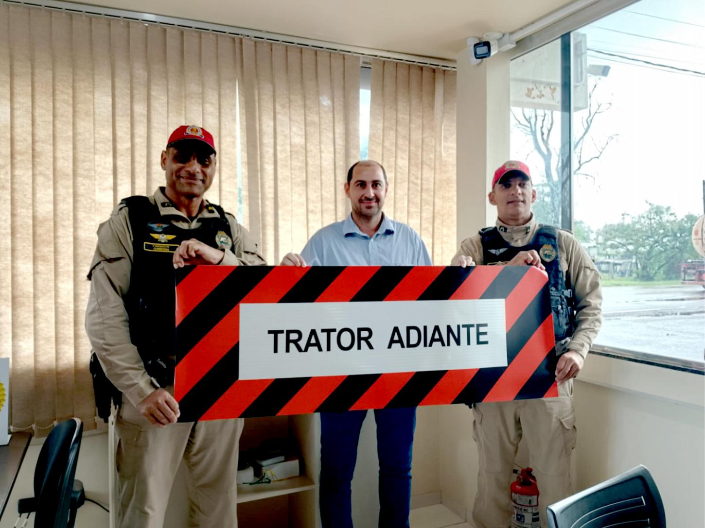 O gerente da unidade da Copacol em Goioerê, Jocimar Bortoluzzi, entrega à Polícia Rodoviária Estadual um modelo de placa de advertência para sinalização de máquinas agrícolas, reforçando a parceria em favor da orientação aos produtores rurais e da seguran